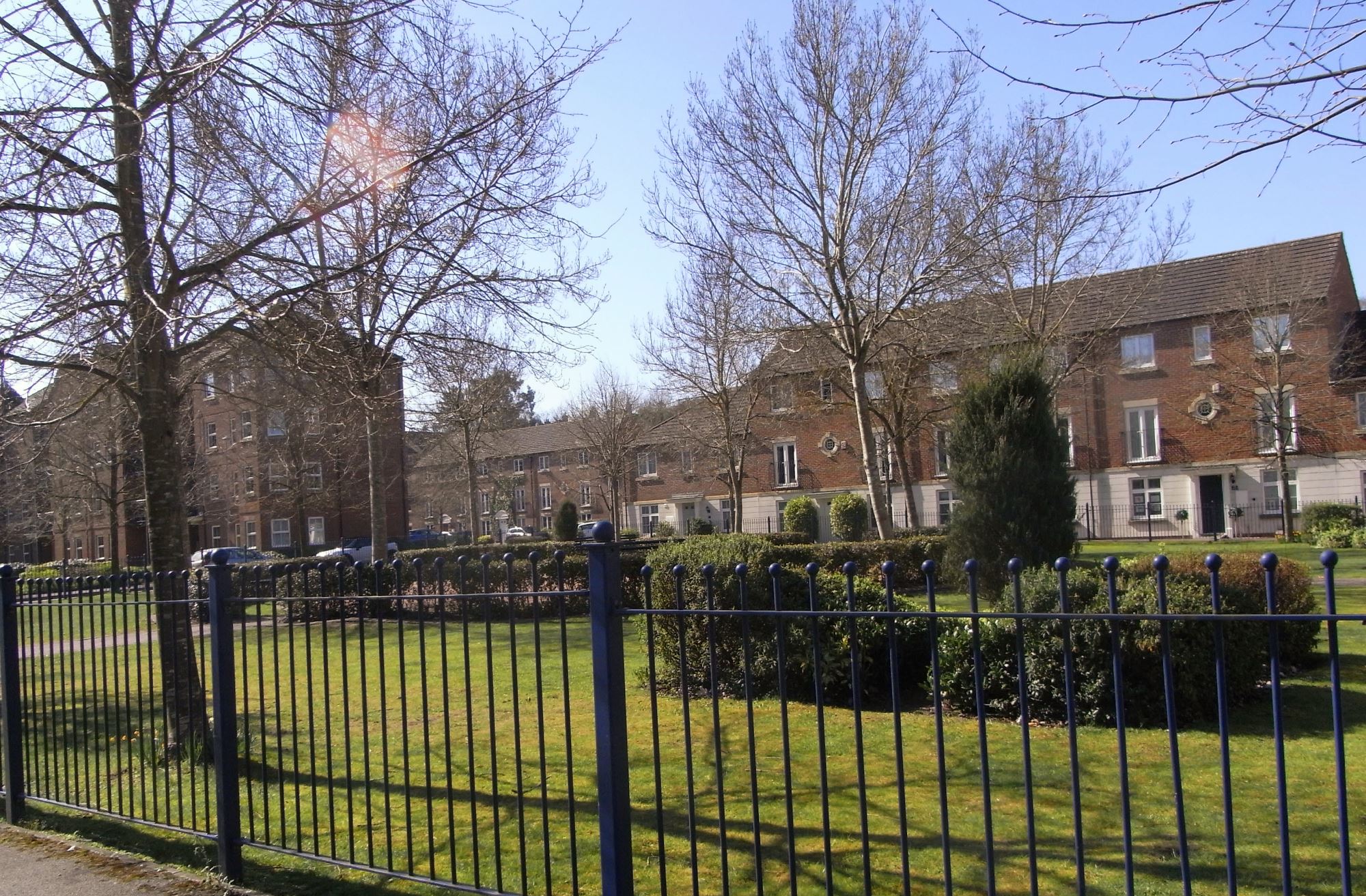 new homes around a green area with railings 